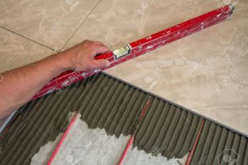 ceramic-tiles-and-tools-for-tiler-worker-hand-installing-floor-tiles-home-improvement-renovation-cer